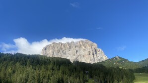 A mountain with a prominent rocky peak, surrounded by dense forest. - Studio apartment in front of Sassolungo mountain (Trentino-Alto Adige)