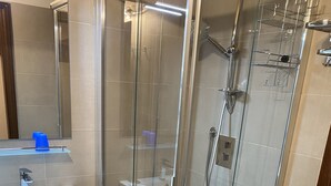 A modern bathroom with a glass-enclosed shower, a white sink, and a toilet. - Studio apartment in front of Sassolungo mountain (Trentino-Alto Adige)