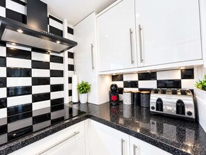 A modern kitchen with black and white checkered backsplash, stainless steel appliances, and white cabinetry. - Beachfront Apt w/ Sea Views & Free Parking (Pevensey)