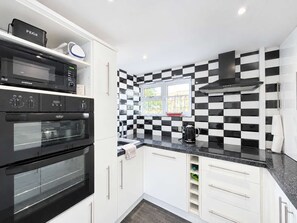 A modern kitchen with a black and white checkered backsplash, a built-in oven, and a window with a view.