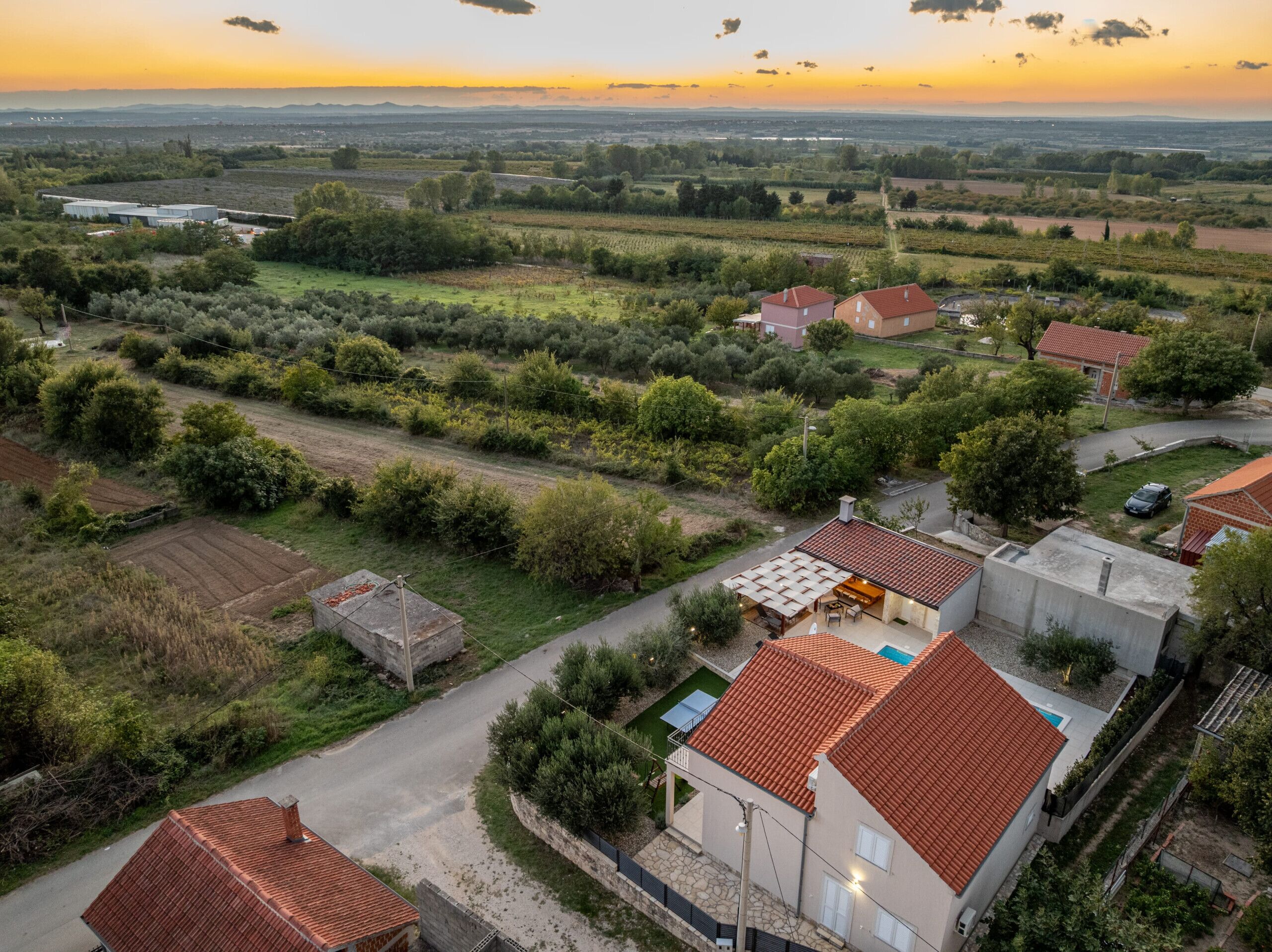 Un quartiere residenziale con case dotate di tetti in tegole rosse, una piscina e un giardino curato.