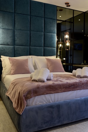 A modern hotel room with a large bed, plush headboard, and ambient lighting.