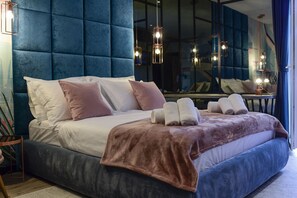 A modern bedroom with a large bed, plush headboard, and multiple pillows.