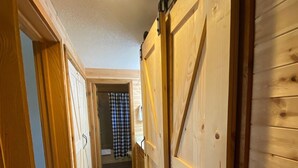 Ein Flur mit Holzwänden und einem Schachbrettfußboden, der zu einem Raum mit einer Tür führt.