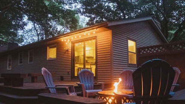 Une cabane en bois dotée d’une terrasse, d’un espace salon extérieur et d’un foyer.