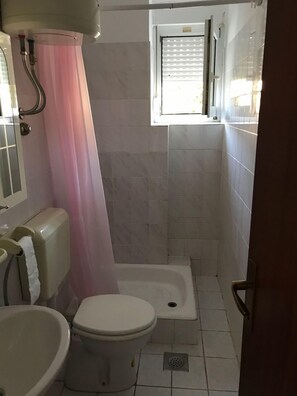 Et badeværelse med toilet, bidet og bruseniche.