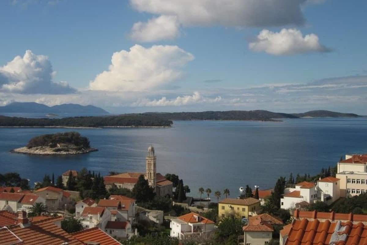 A coastal town with a prominent church tower, a small island, and a clear view of the sea.