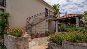 Ein Gebäude mit einer Steintreppe, die zu einem Balkon führt, umgeben von Topfpflanzen und Blumen.