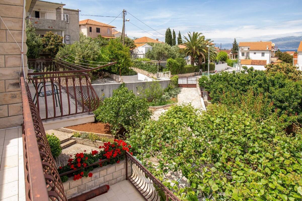 Un quartier résidentiel avec des balcons, un jardin agrémenté de fleurs rouges et des maisons aux toits de tuiles.