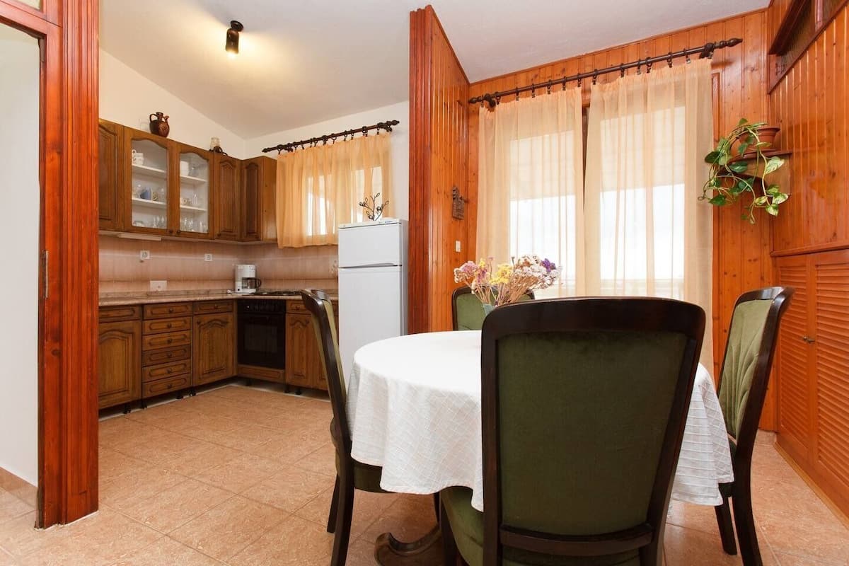 Una cocina con armarios de madera, un refrigerador blanco y una mesa de comedor con sillas.