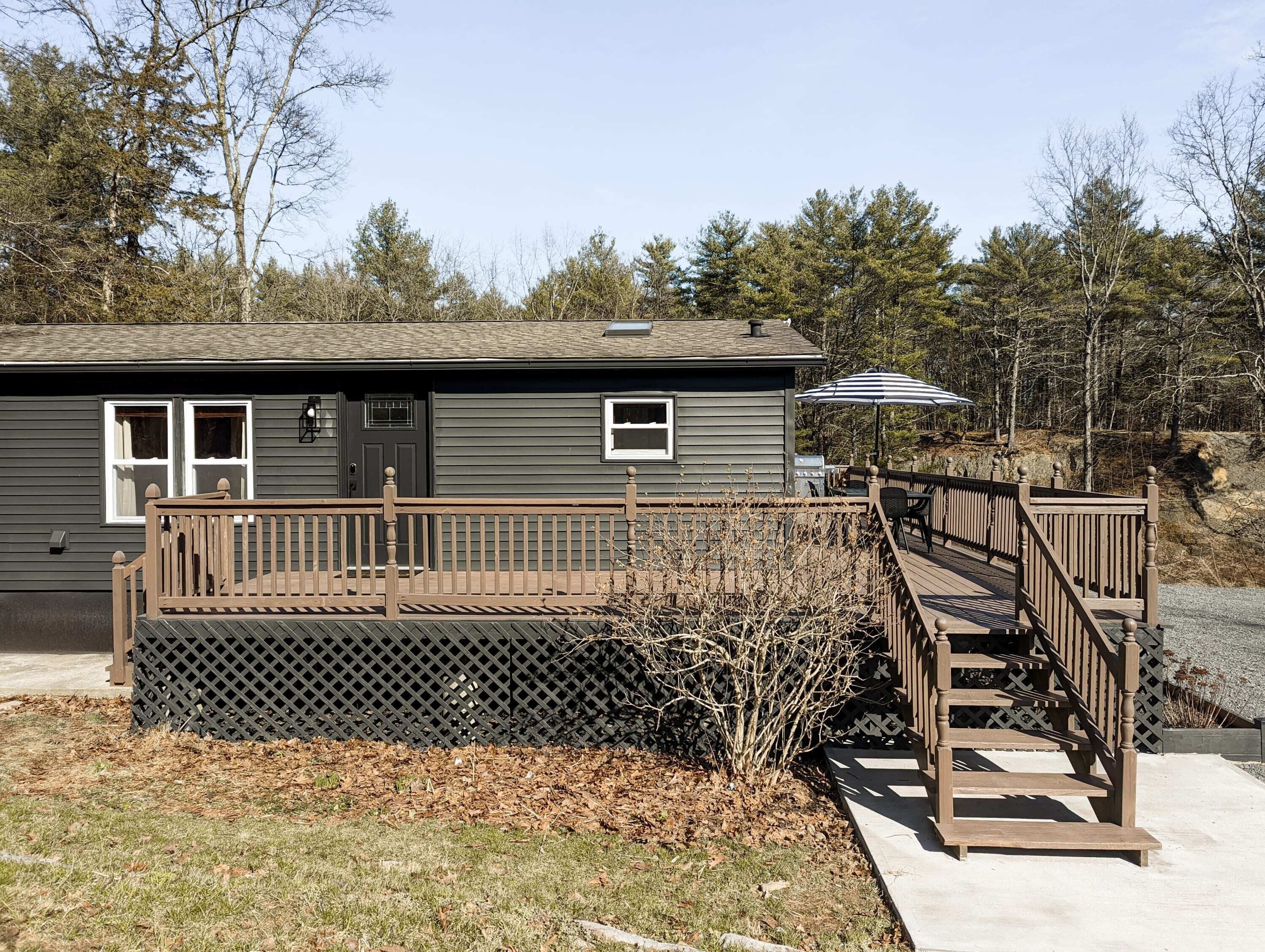 A two-story house with a wooden deck, a covered patio, and a staircase leading to the deck.