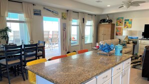 A kitchen with a granite countertop, white cabinetry, and a dining area with chairs and a table. - Island life, Island time, After Dune Delight (Freeport)