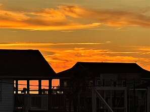 Un coucher de soleil sur une zone résidentielle, avec des maisons et une ligne électrique visible.