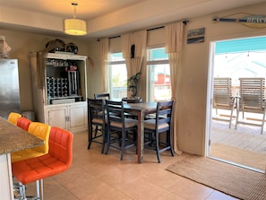 A dining area with a table and chairs, a refrigerator, a wine rack, and a view of the outside. - Island life, Island time, After Dune Delight (Freeport)