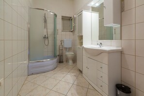 Un bagno con doccia, toilette, lavandino e armadietti.