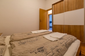 Camera d'albergo con due letti, un armadio in legno e una porta che conduce al bagno.
