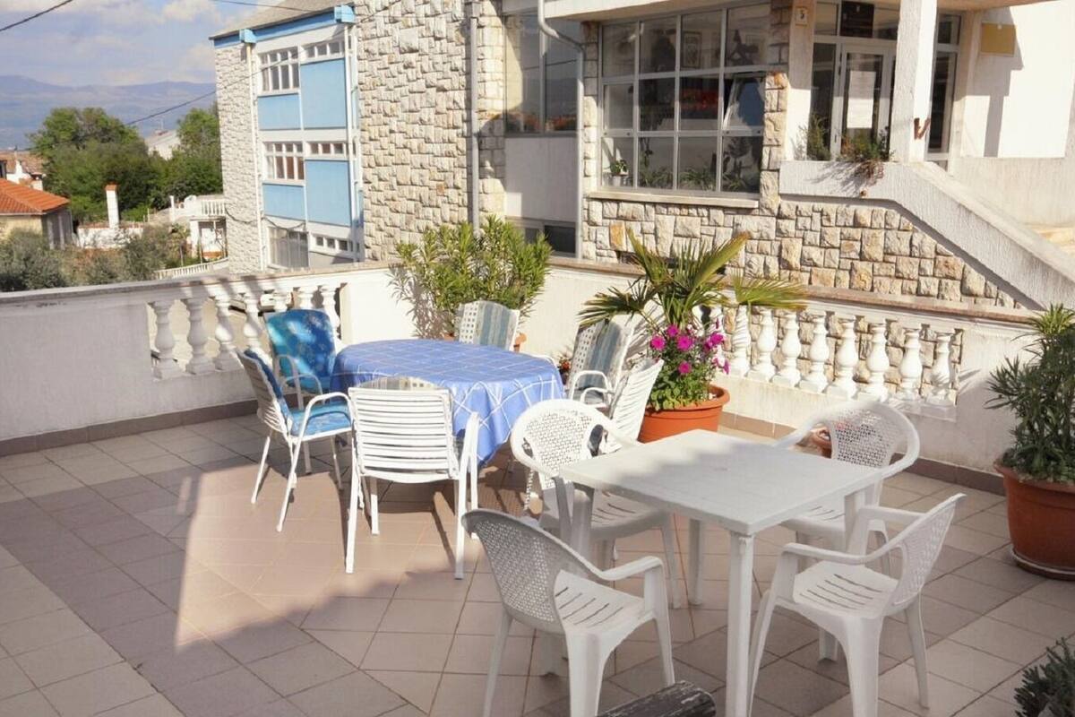 A terrace with a table and chairs, potted plants, and a stone wall.