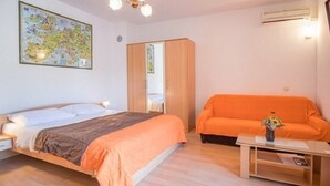 Ett sovrum med en säng, en orange soffa, en trägarderob, en karta på väggen och en luftkonditioneringsanläggning.