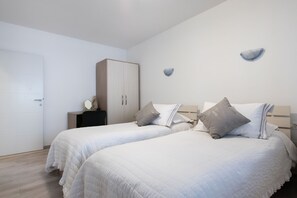 A bedroom with two beds, a wardrobe, a nightstand, and wall sconces. - Snjezanal- in the Center - A1 (Split)