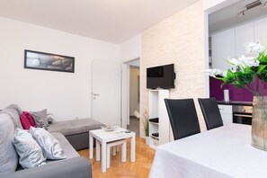 A modern living room with a grey sofa, a small white table, and a dining area with a white tablecloth. - Snjezanal- in the Center - A1 (Split)