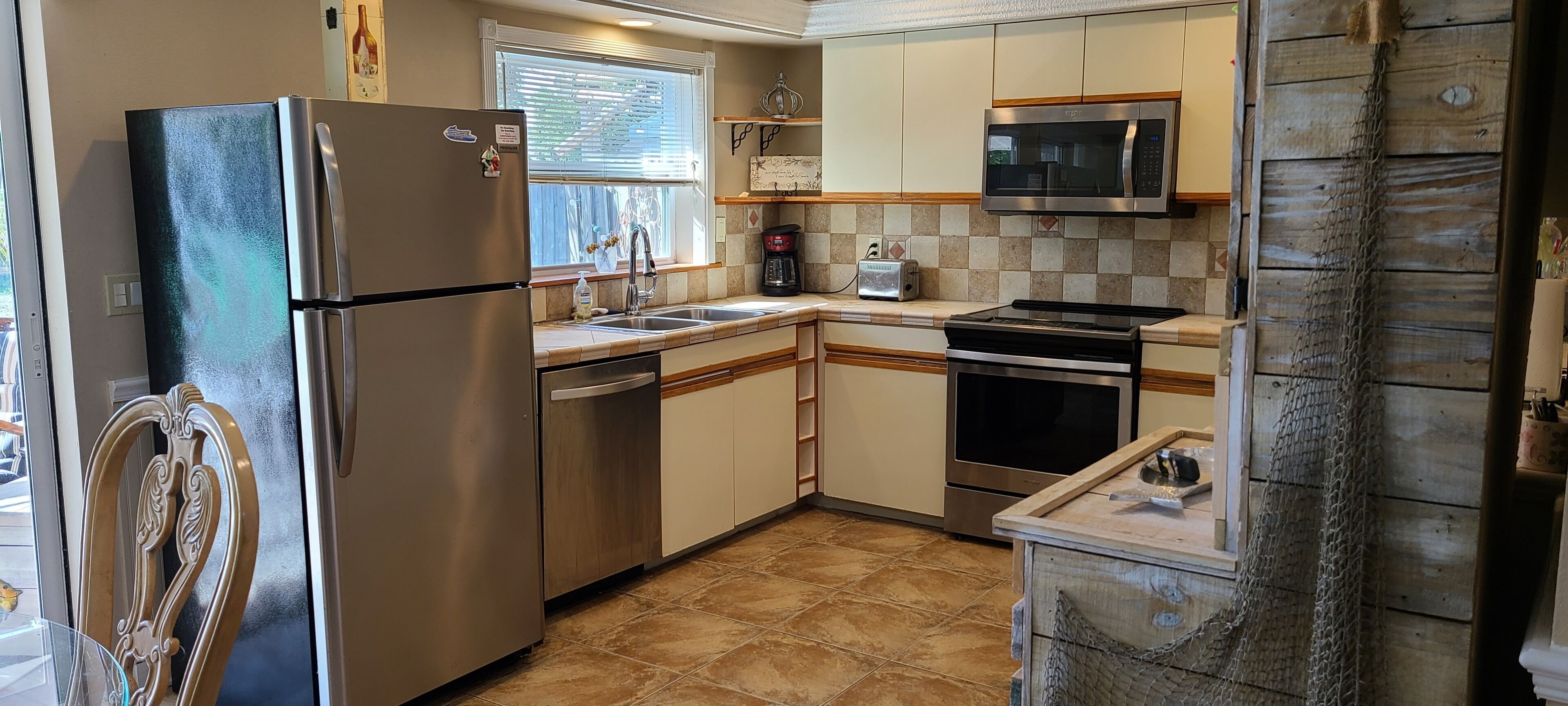 A compact kitchen with a refrigerator, microwave, stove, and sink.