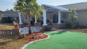 A residential property with a covered patio, a lawn, and a variety of plants. - Minutes to gulf beaches, great outdoor space, putting green,perfect getaway  (Englewood)