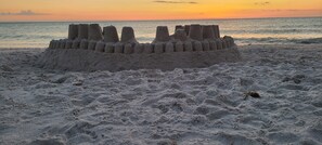 A sandcastle on a beach at sunset.