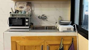 Une cuisine de taille réduite, dotée de meubles en bois, d’un four à micro-ondes, d’une cuisinière à gaz et d’une fenêtre.