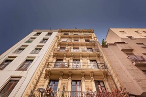 A multi-story building with ornate architectural details, balconies, and a clear sky.
