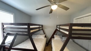 Ein Zimmer mit Etagenbetten, einem Deckenventilator und einem Fenster.