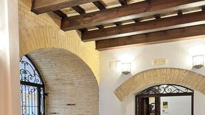 A cozy café with round wooden tables and grey upholstered chairs. - Hotel Servilia (Carmona)