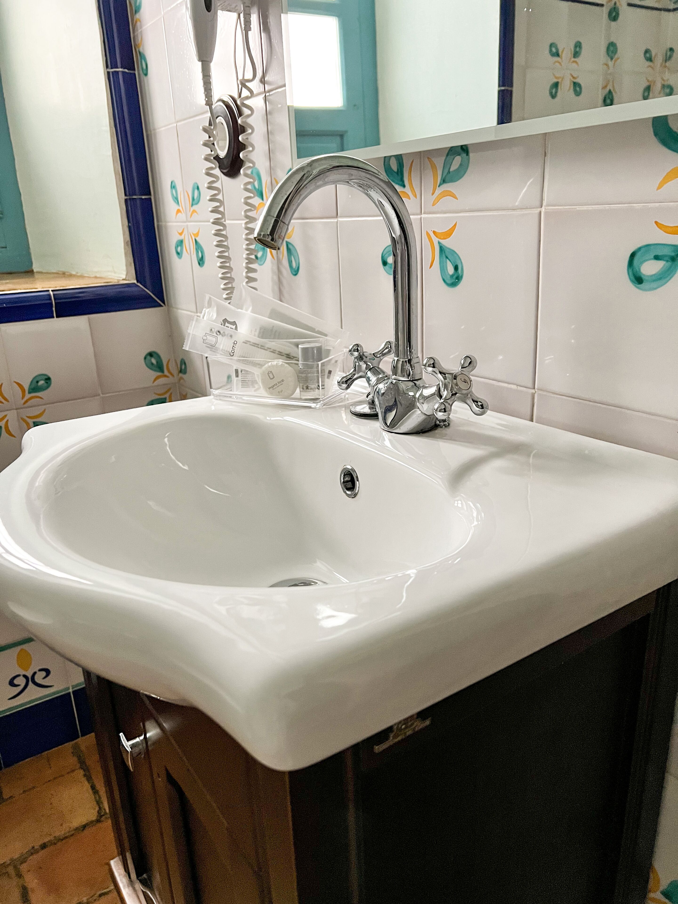A bathroom with a white sink, a chrome faucet, and a mirror above it.