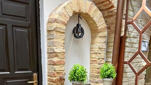 A stone-built outdoor area with a black door, a white wall, and a decorative metal gate. - Hotel Servilia (Carmona)