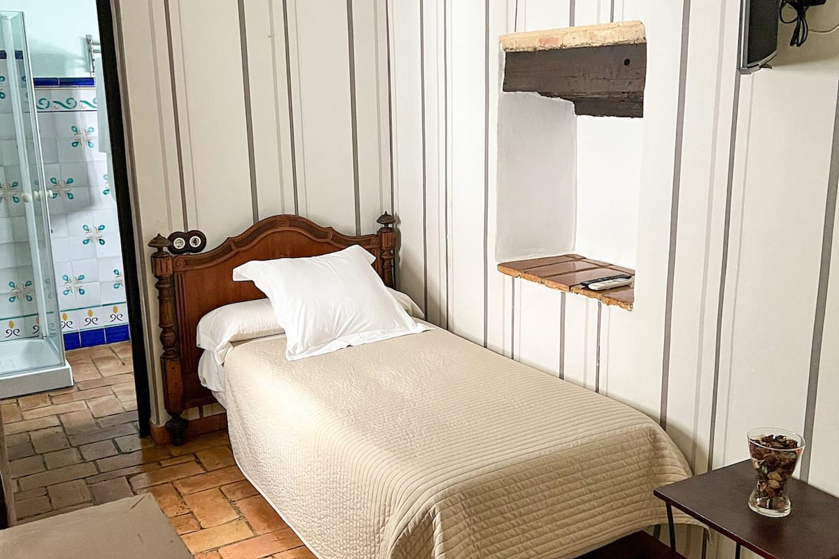 A bedroom with a wooden bed, a small table, and a shelf.