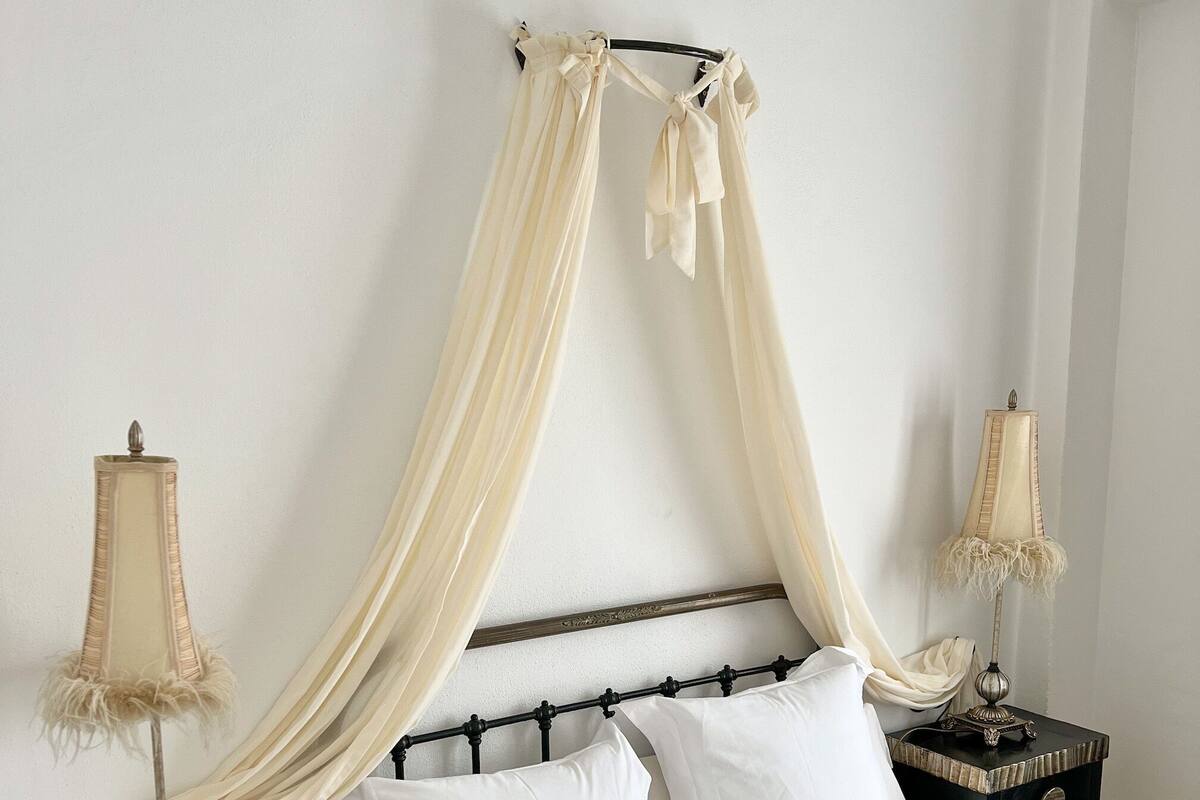 A bed with a canopy, two bedside tables with lamps, and a patterned bedspread.