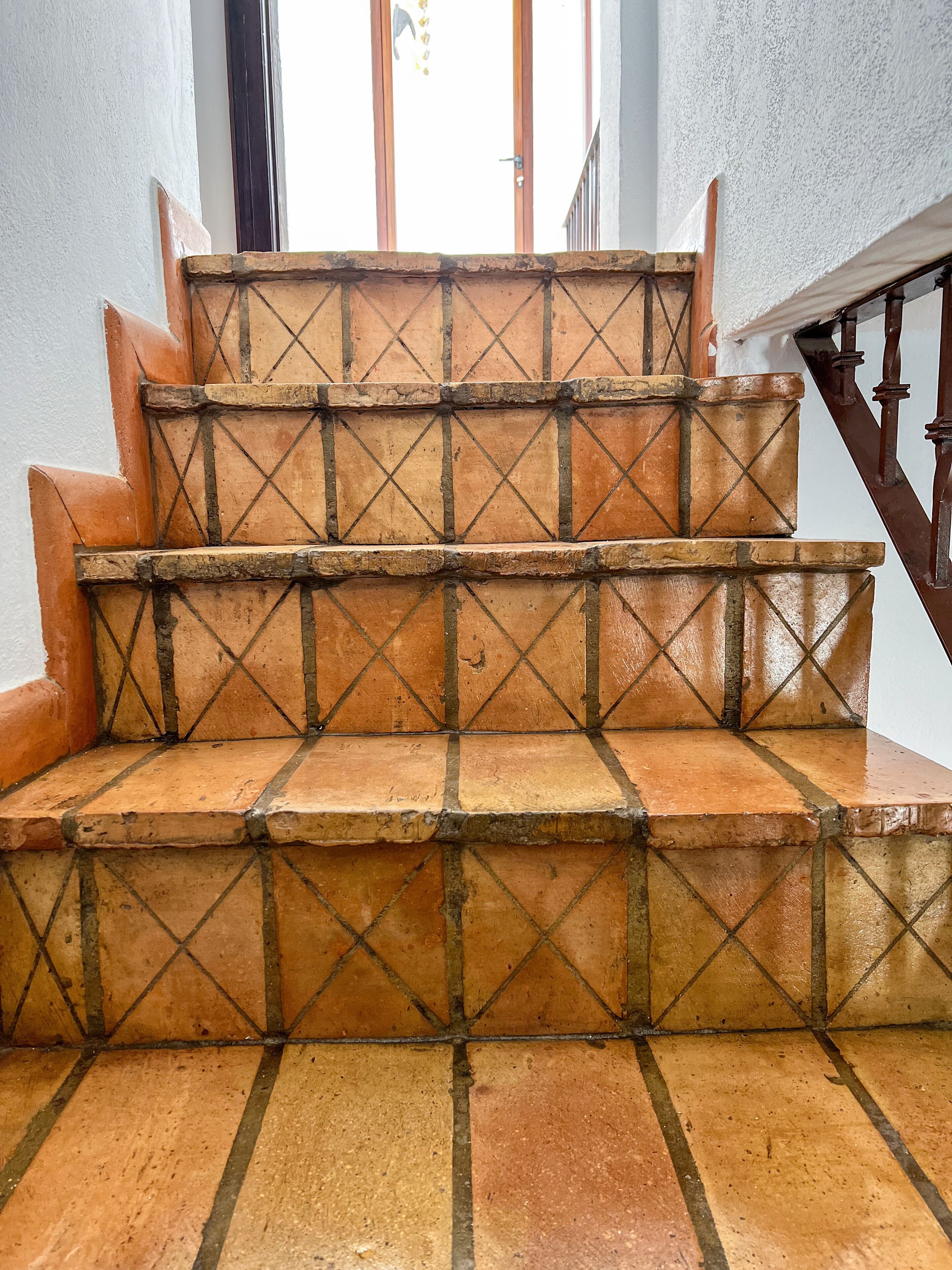 Una escalera con baldosas de terracota y barandillas de madera.