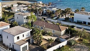 Un área residencial costera con casas modernas, algunas con techos de tejas, y palmeras.