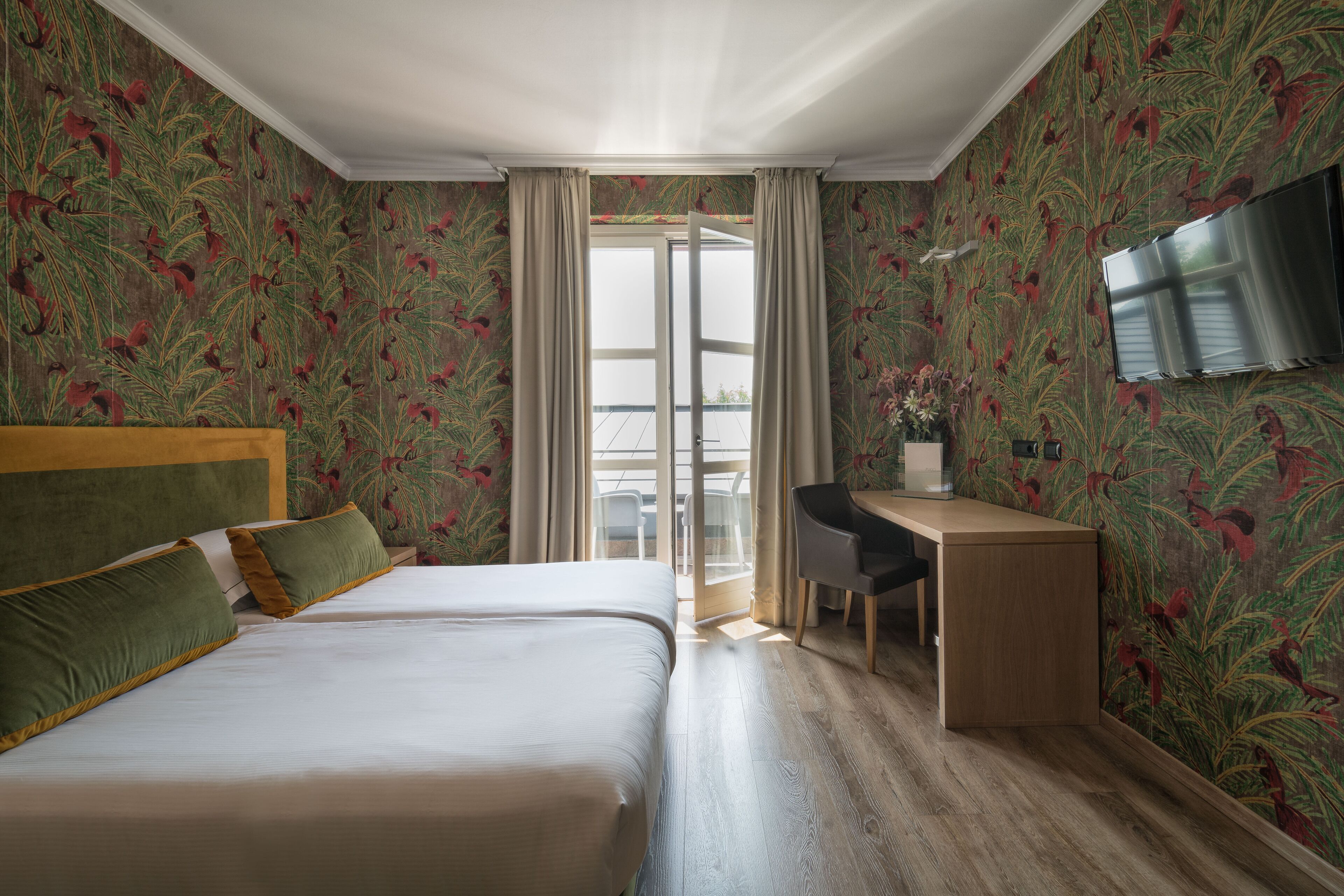 A hotel room with a bed, a desk, and a TV.