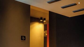 Un moderno sector de recepción de hotel con mostrador, luces en el techo y un espacio interior visible con asientos.