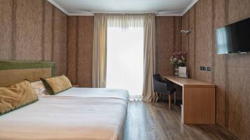 A hotel room with a large bed, a desk, and a TV.