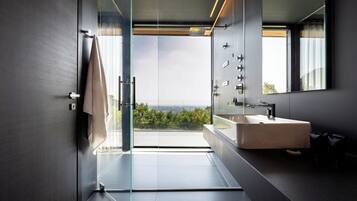 A modern bathroom with a large mirror, a beige sink, and a glass shower enclosure.