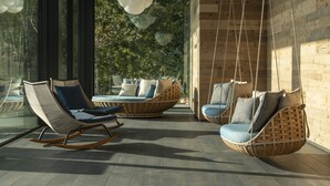 A modern interior with wicker furniture, large windows, and a hanging light fixture. - Phi Hotel Piajo (Nembro)
