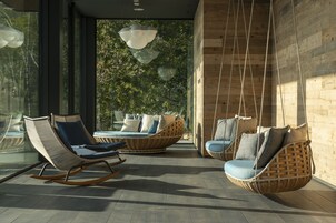 Un interior moderno con mobiliario de mimbre, ventanas amplias y una lámpara colgante.