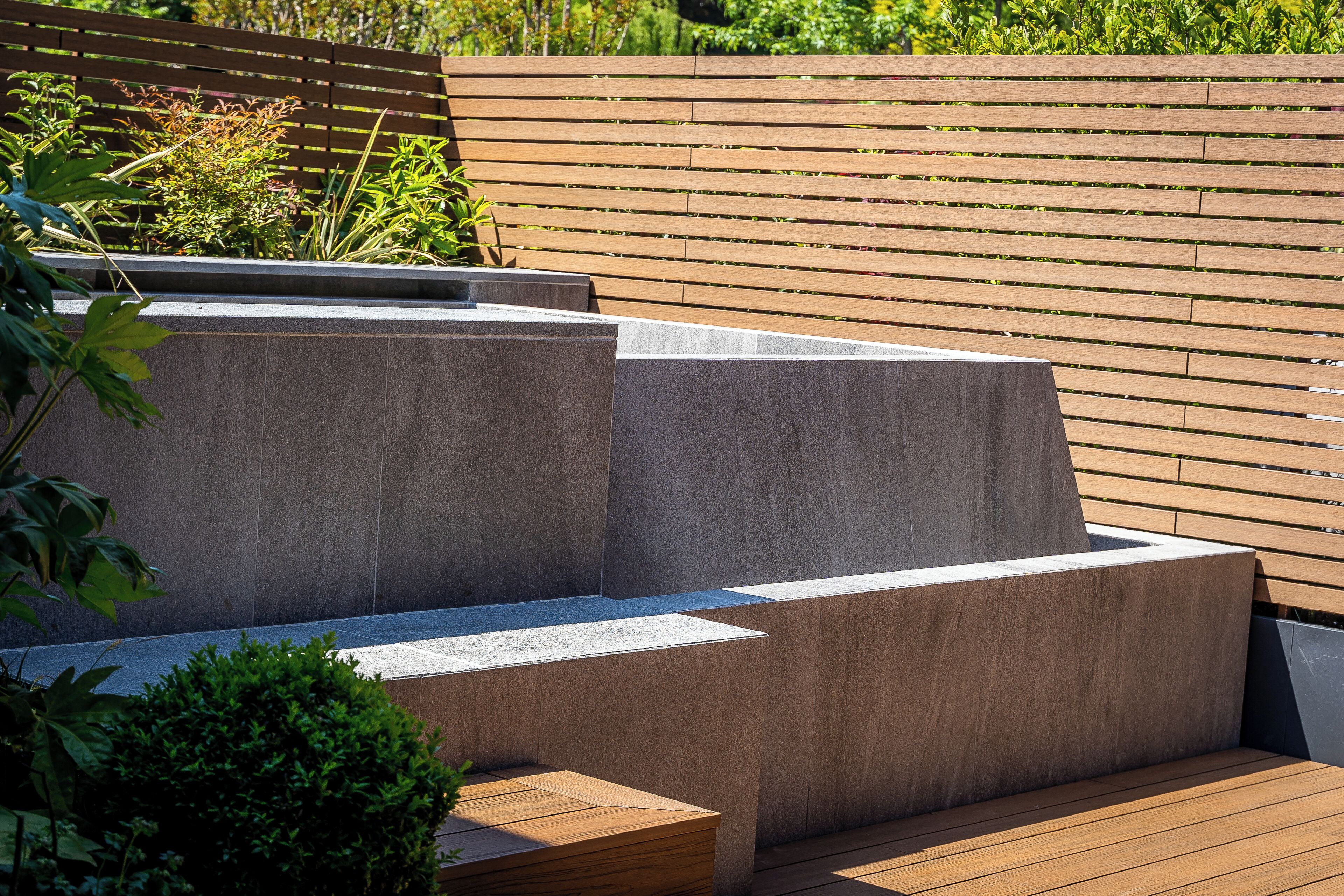 A modern outdoor seating area with tiered concrete steps and wooden benches.