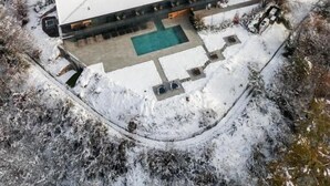 A large, modern building with a swimming pool, surrounded by snow-covered grounds and trees. - Phi Hotel Piajo (Nembro)