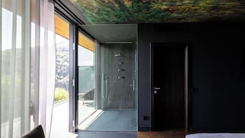 Quarto moderno com uma grande janela, uma cama e área de chuveiro.