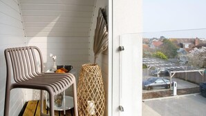 Un balcon avec une chaise, un panier en osier et une vue sur un quartier résidentiel.