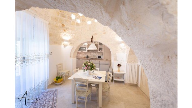 Una cocina acogedora y rústica con paredes de piedra, una isla central y una zona de comedor con mesa y sillas.
