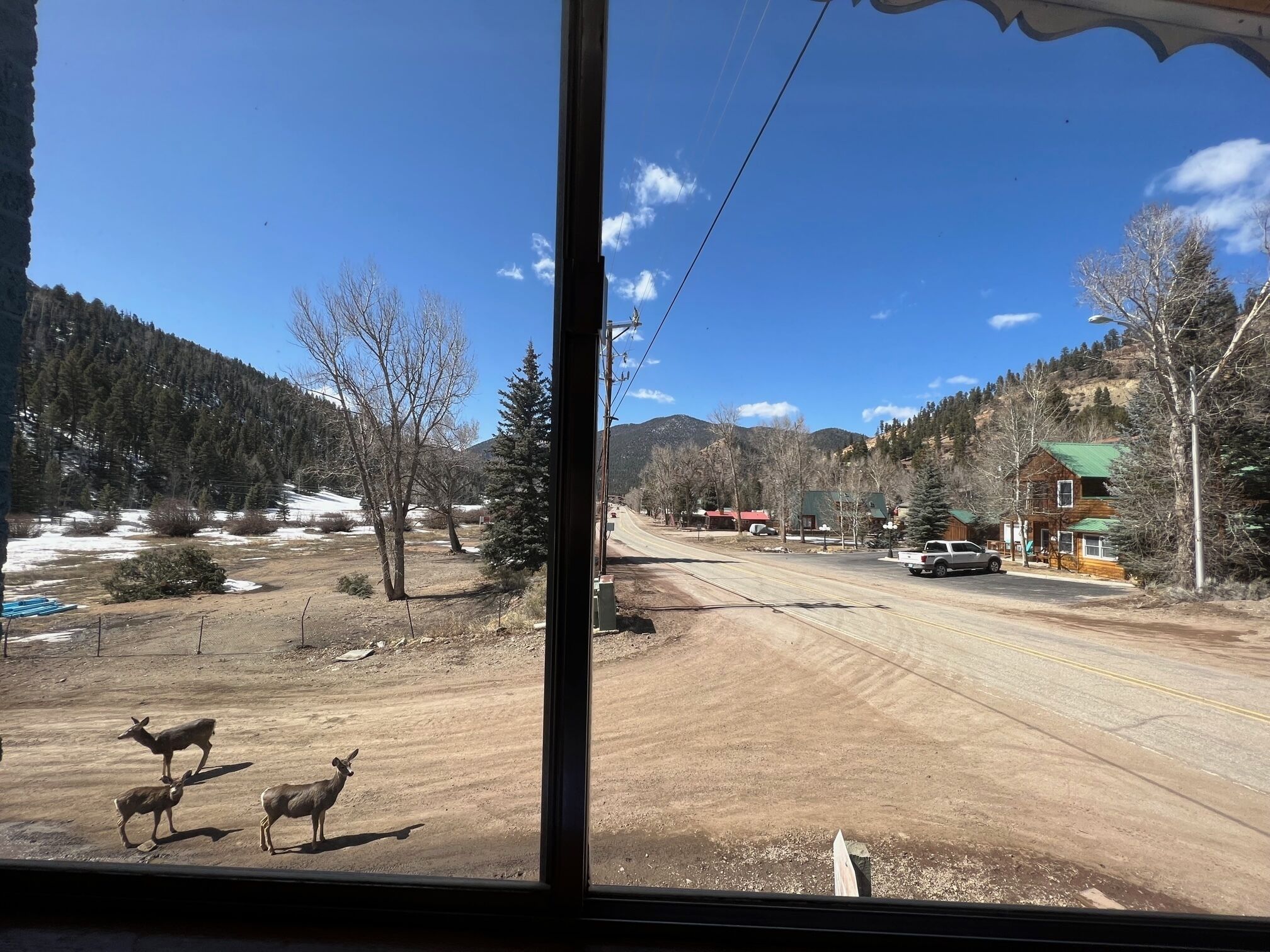 A view from inside a building looking out at a rural road with a few buildings and trees.