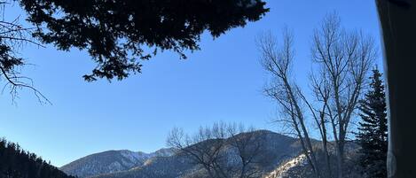 A snowy landscape with mountains, trees, and a clear sky.